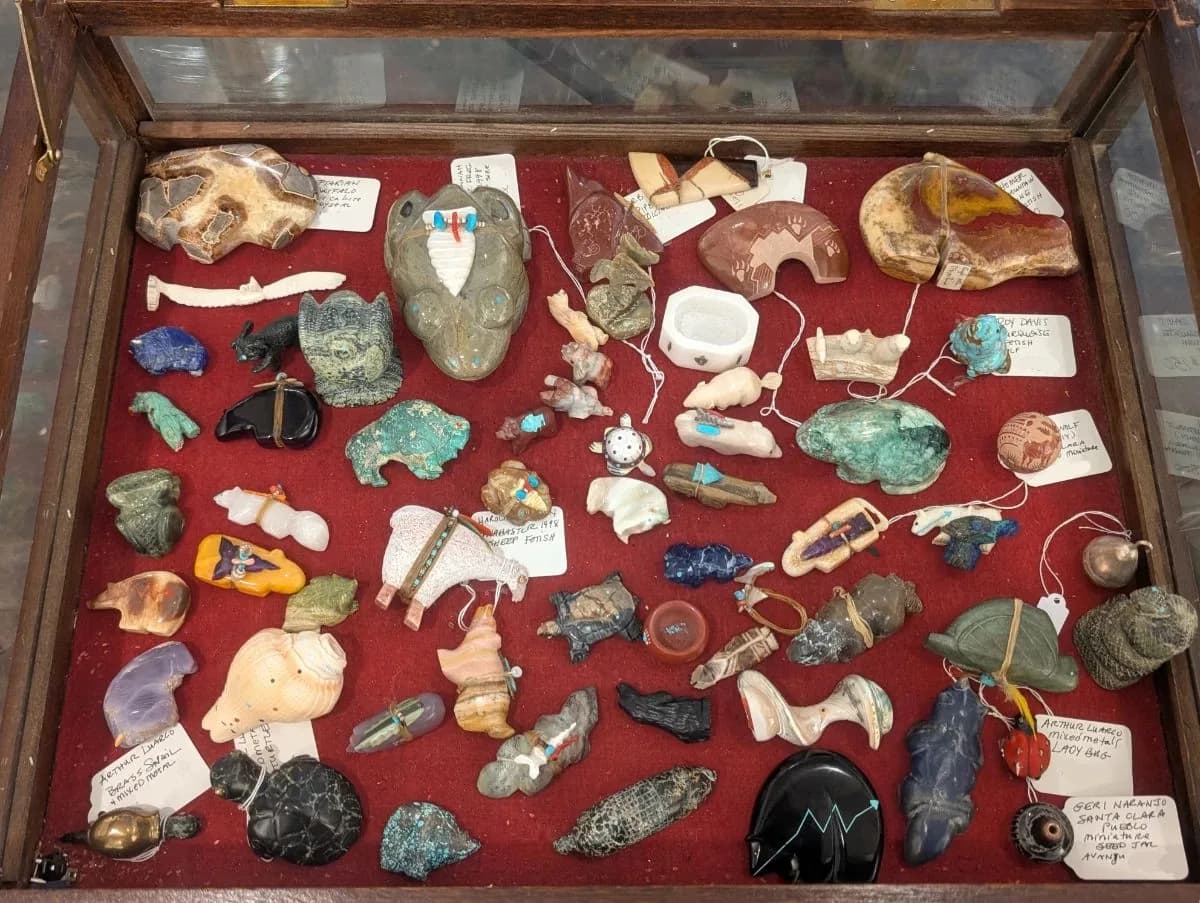 Display case of carved stone fetish figures and Pueblo pottery at a Houston estate sale